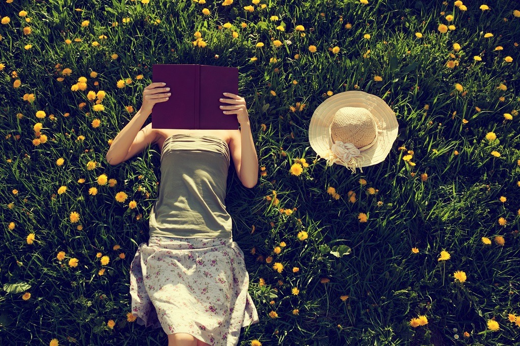 Girl lying in grass, reading a book.