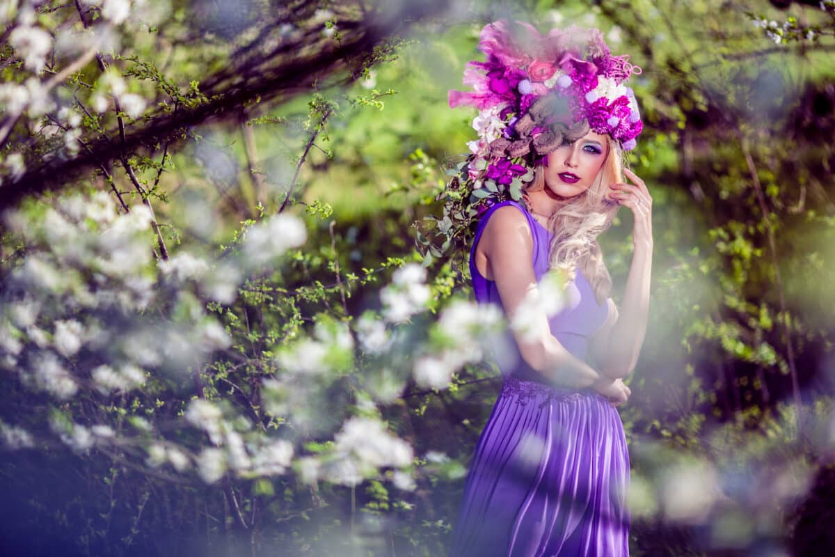 Fairy in purple dress wears a pink flower head wreath