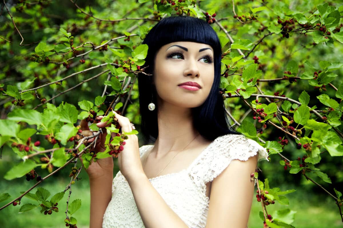 a beautiful woman enjoying next to mulberry plant