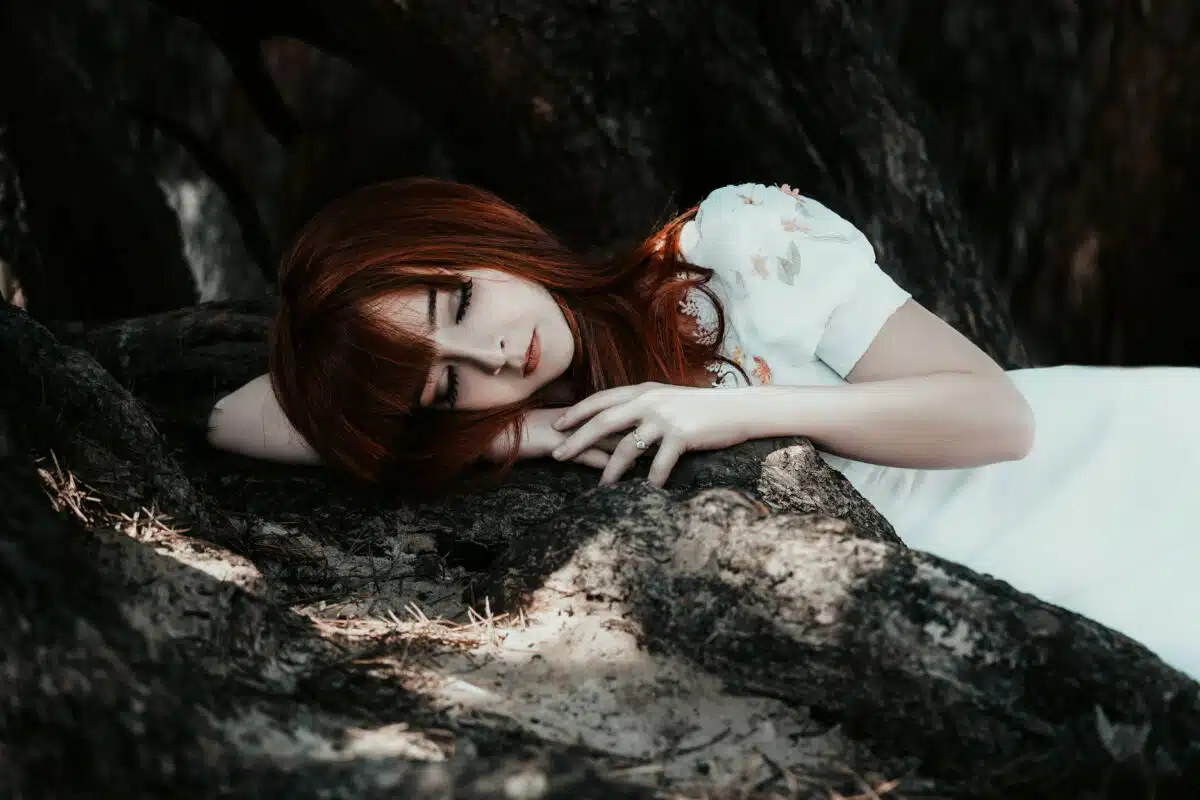 red haired lady lying in the mystical and mysterious forest