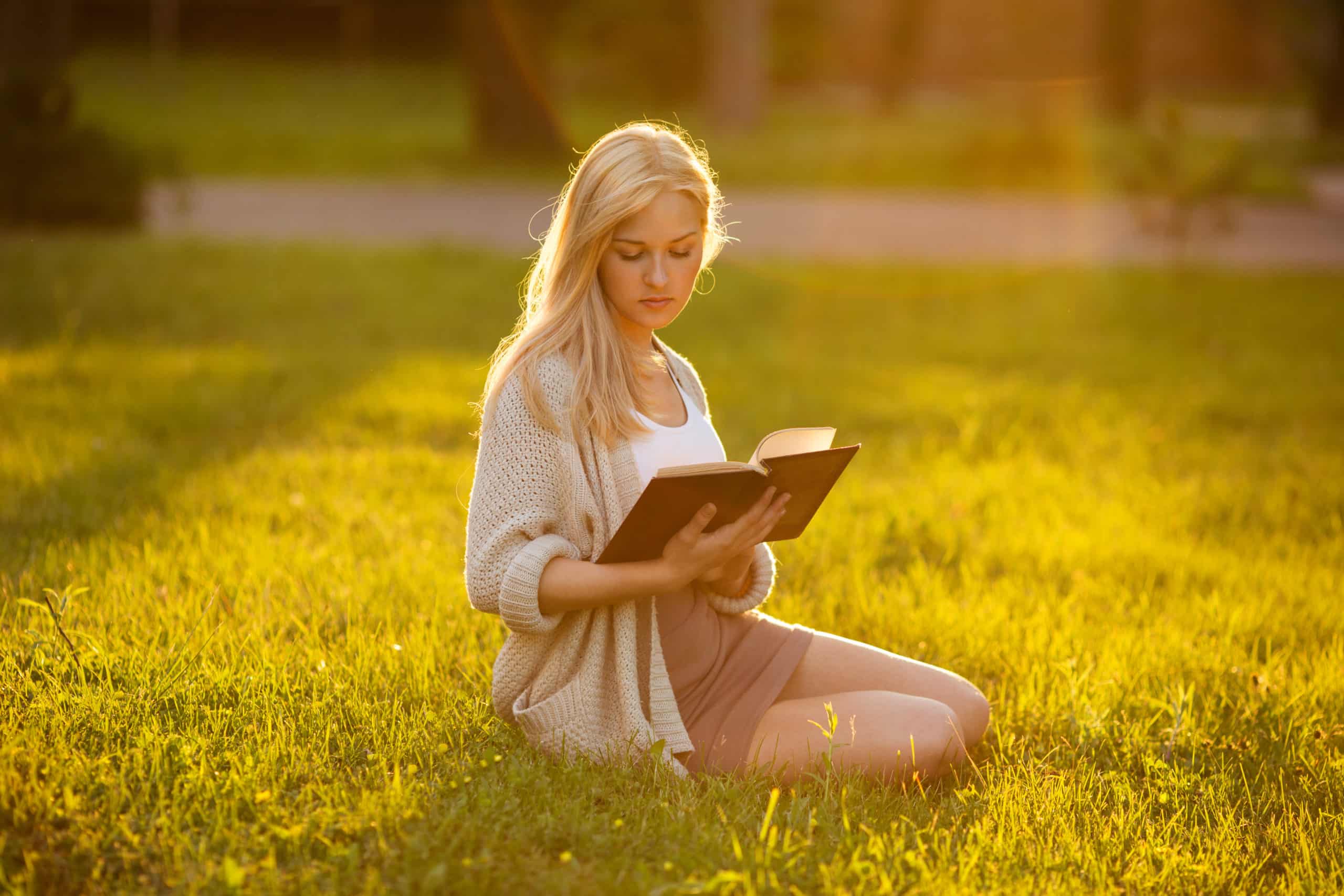 Girl sitting on the grass and reading a book.