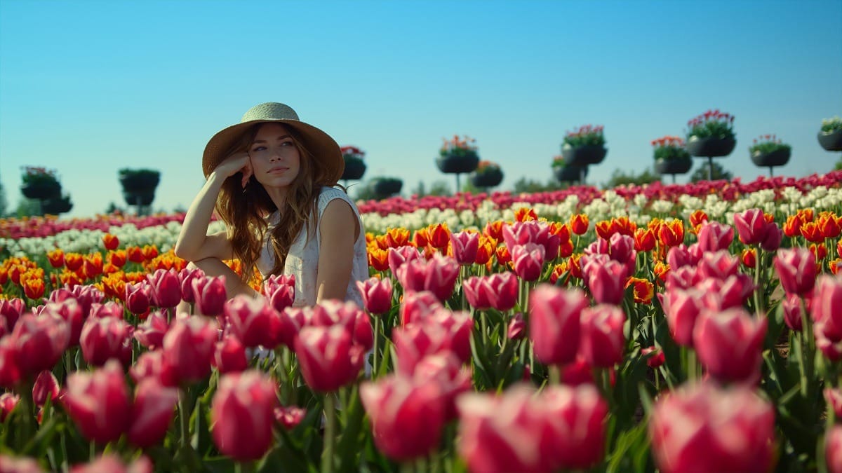 Relaxed woman sitting in beautiful red tulips garden.