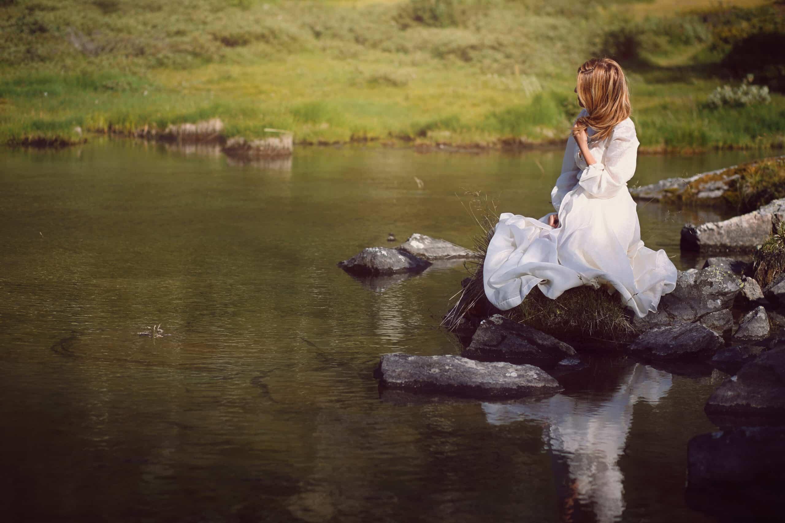 Romantic woman seated on lake rocks