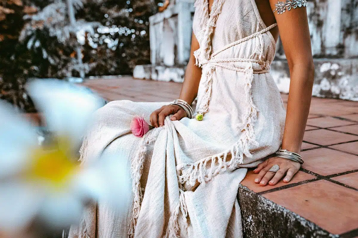 young woman holding a flower in beautiful white dress sitting outdoor