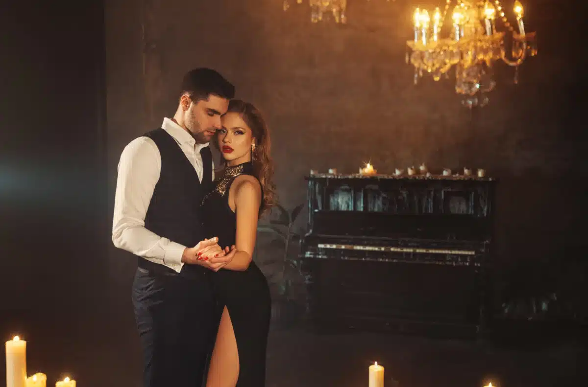 sensual couple in dark gothic room with piano and candles burning