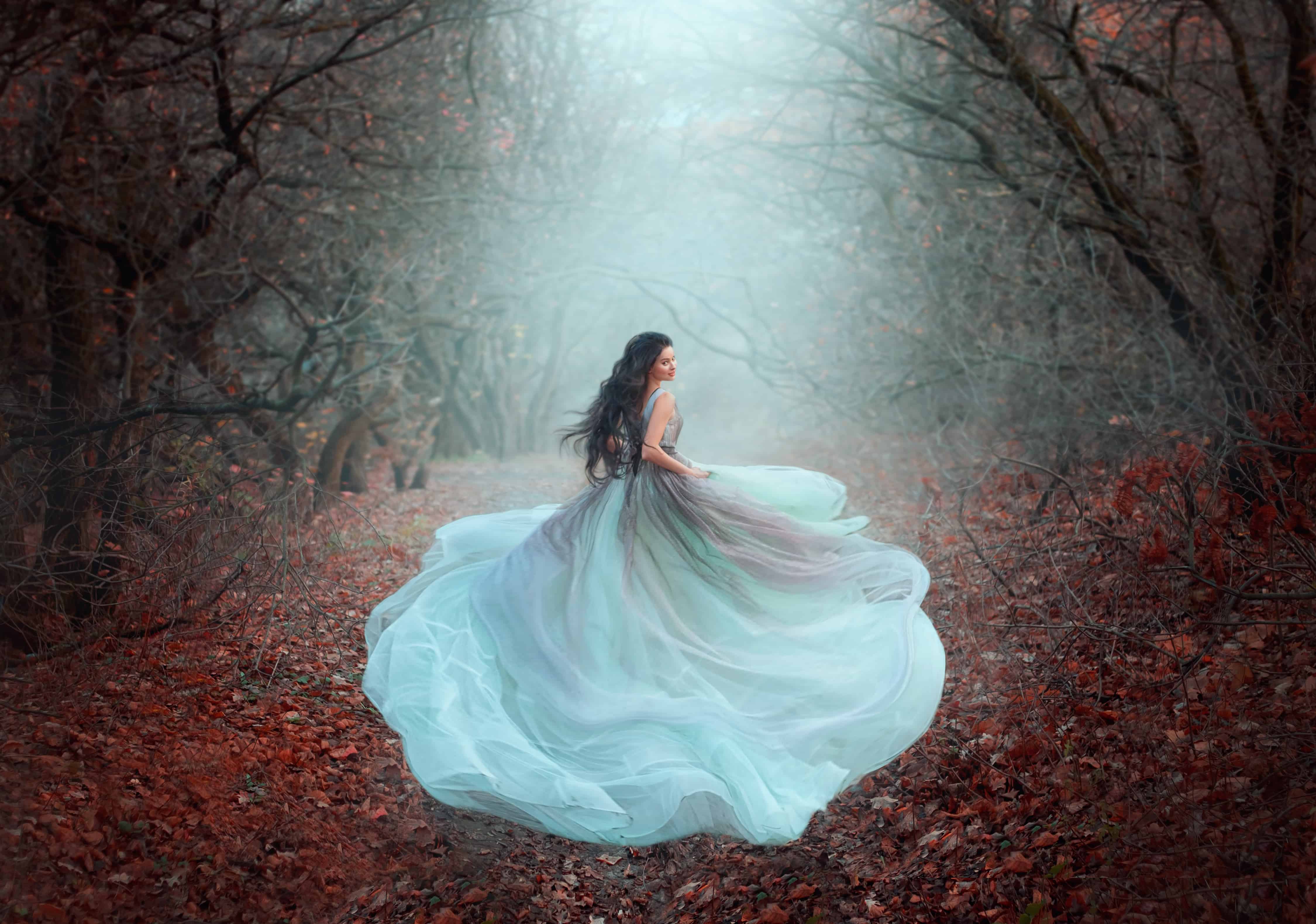Blurred silhouette of running fairy girl in motion. Beautiful woman fantasy princess in lush dress. dark deep forest black trees fog orange fallen autumn leaves, foliage. fabric of skirt flies in wind