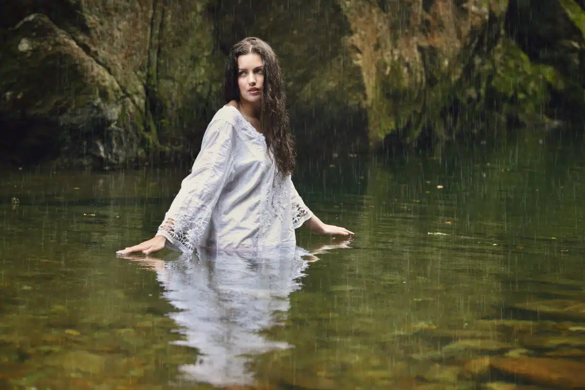 mysterious woman in a white dress in a forest stream