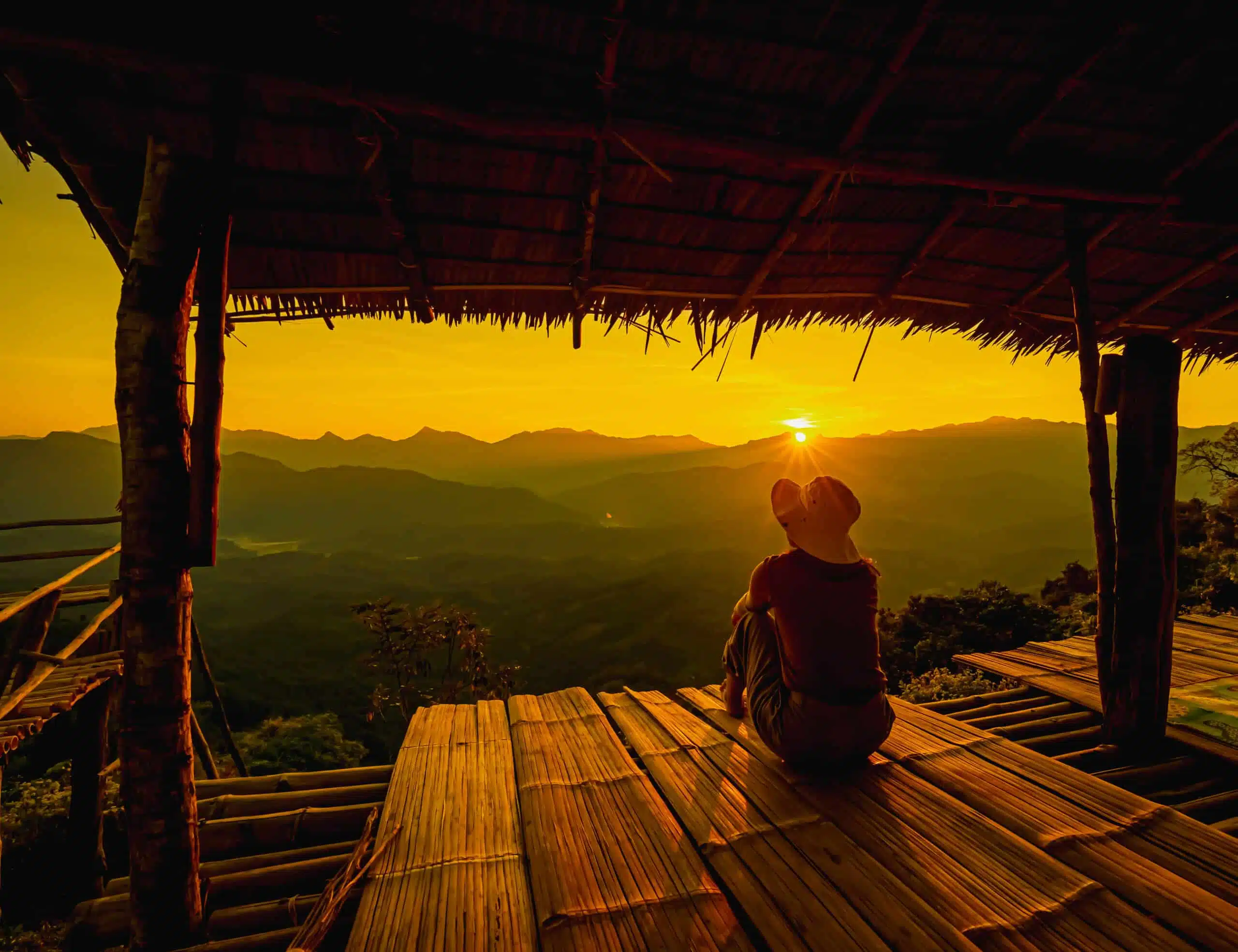 Picture from the back of a woman sitting on wooden porch extendi