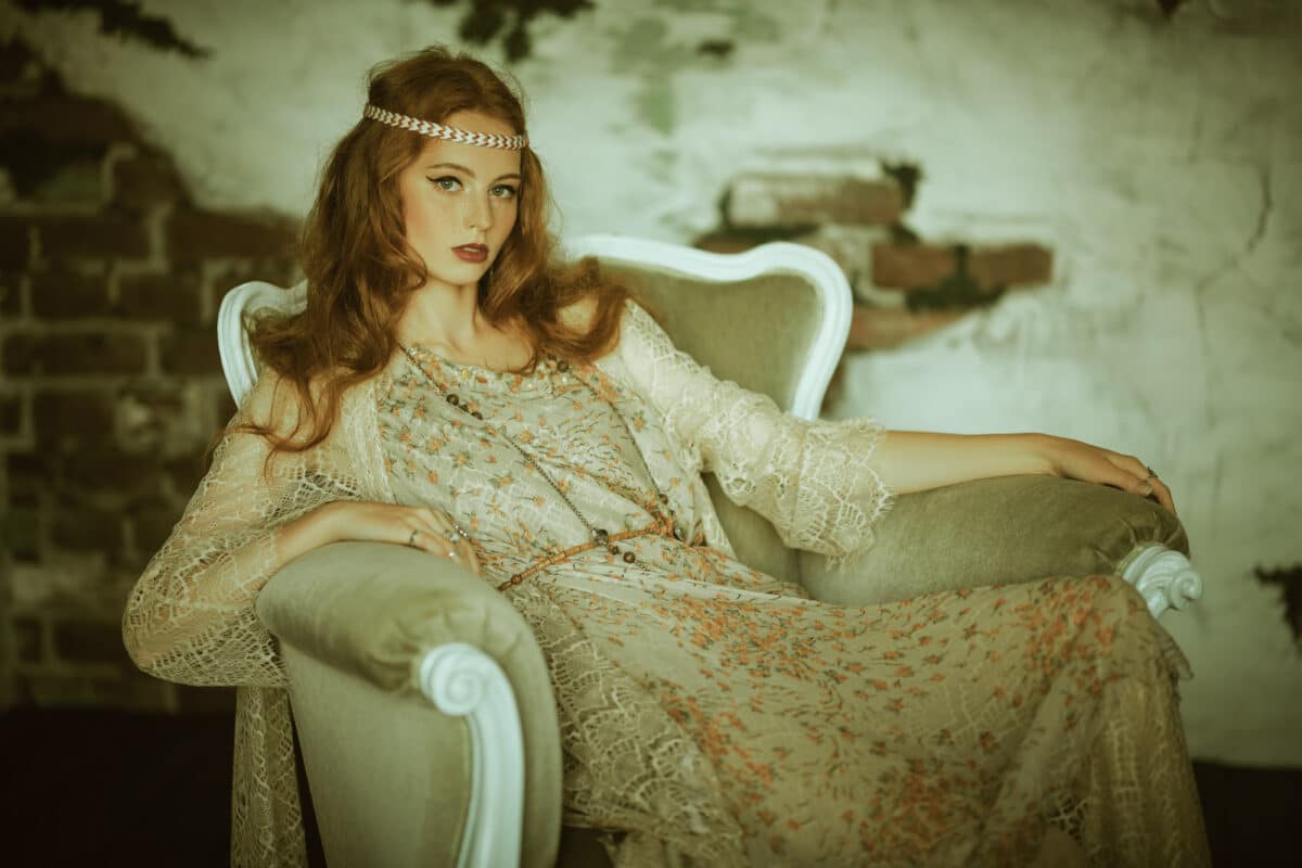 a beautiful red-haired young woman sitting in vintage armchair