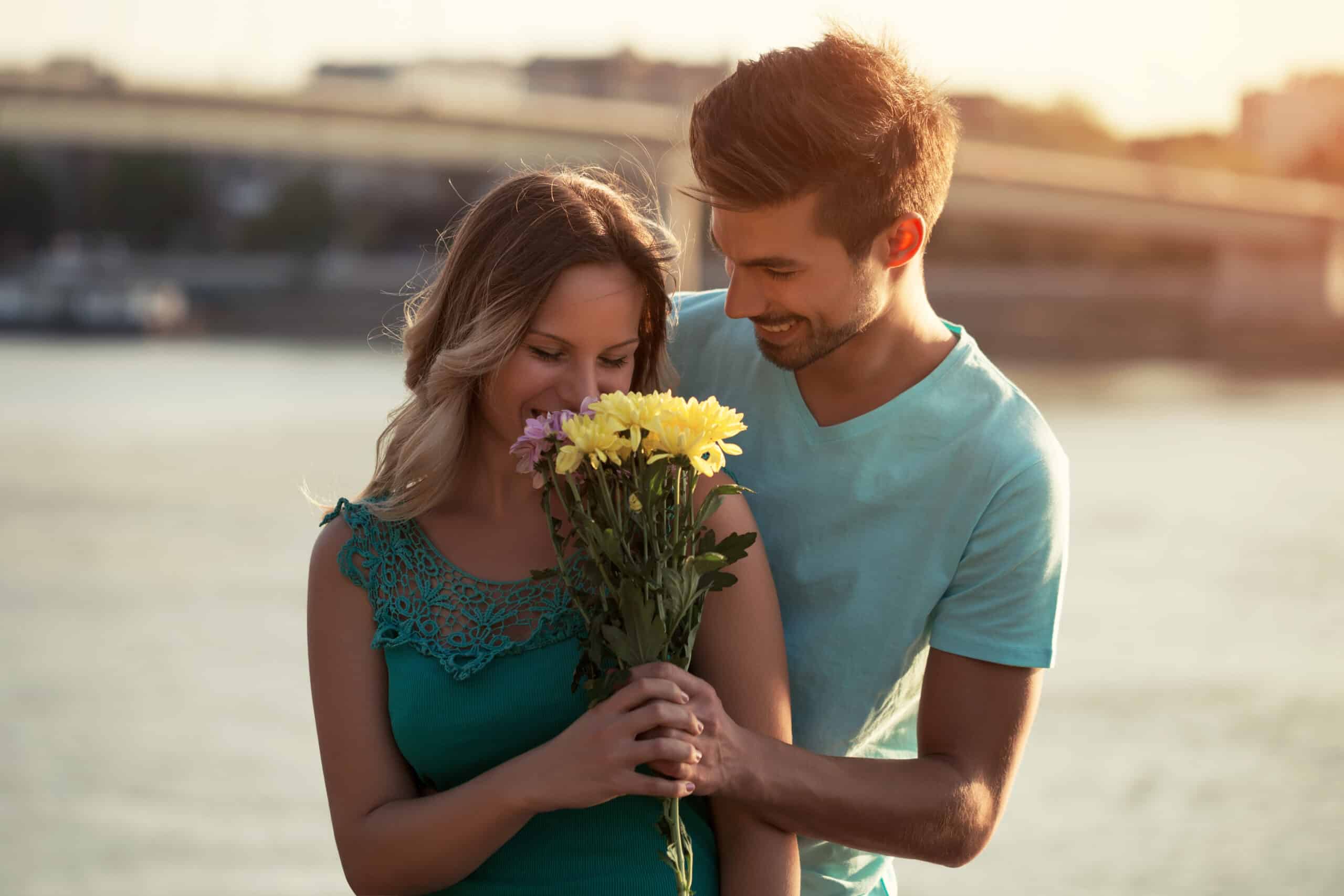 Young man is giving beautiful bouquet of flowers to his girlfriend
