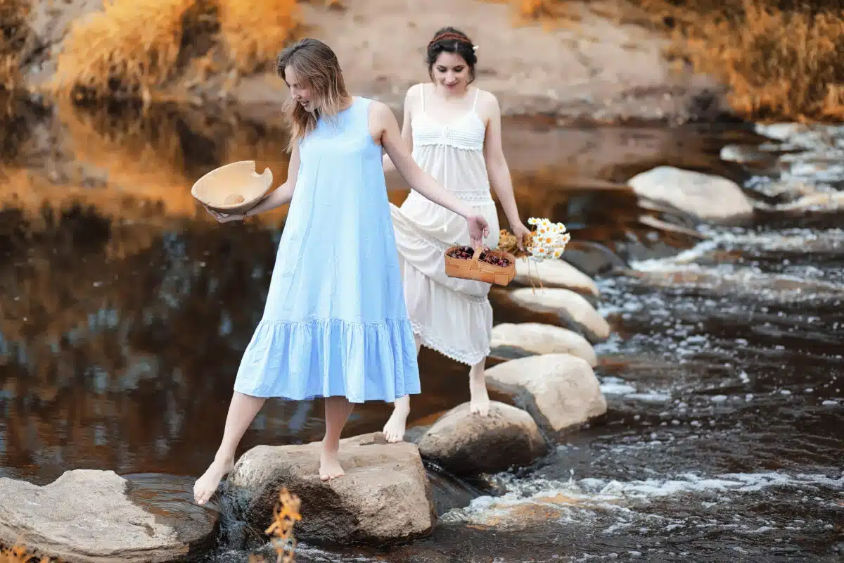pretty ladies in dresses walking on rock paths on the river