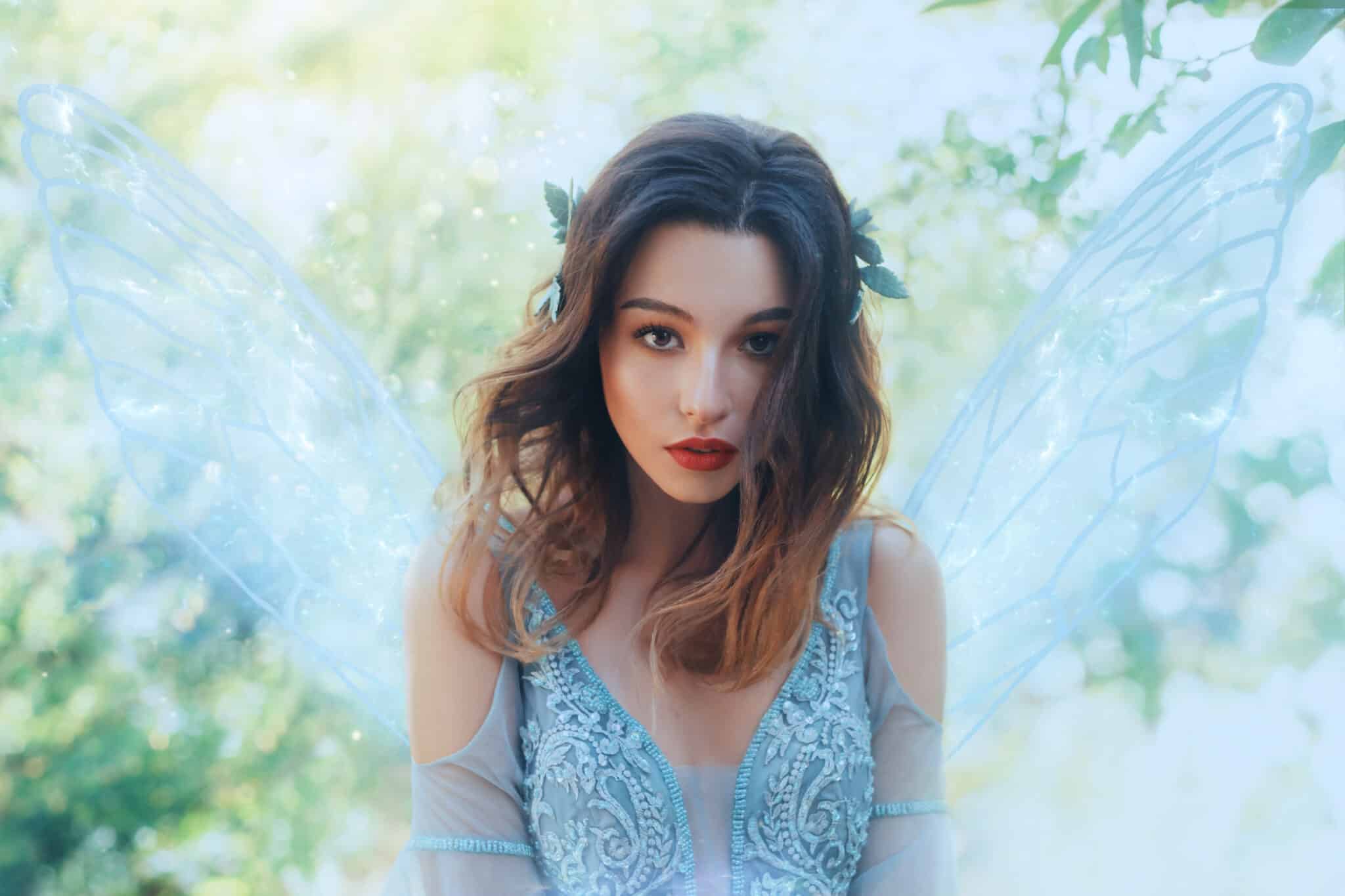 Fantasy closeup portrait attractive woman in image young fairy. carnival Costume blue dress transparent wings. 