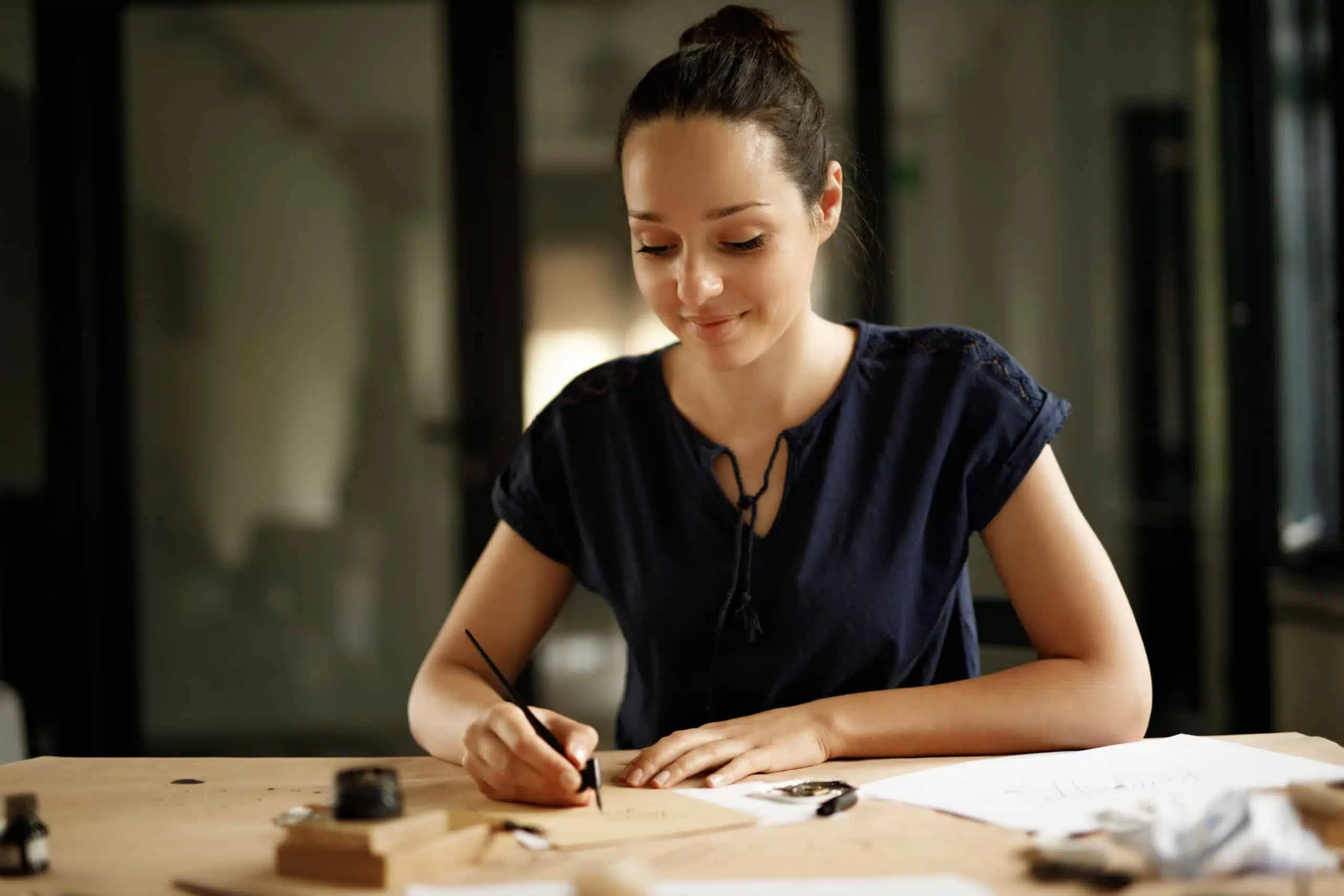 Beautiful smiling young woman writing with fountain pen.