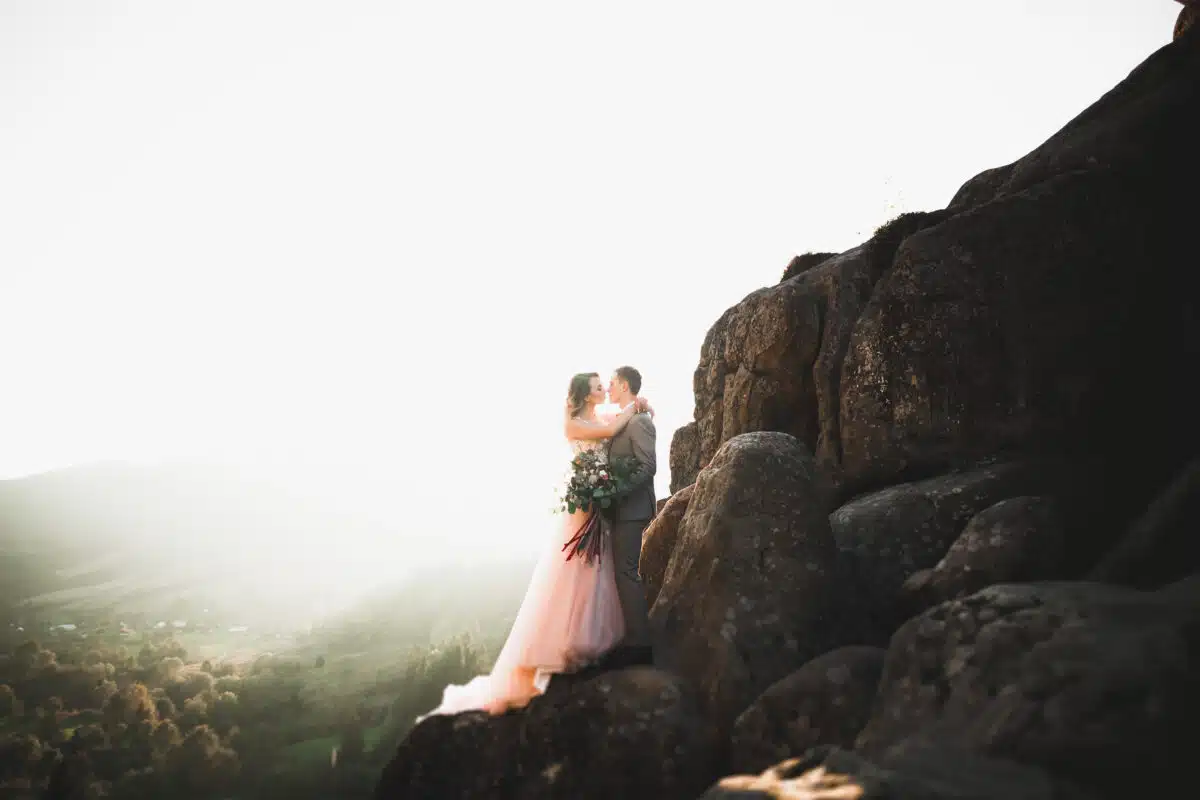 Happy bride and groom on wedding day outdoors on the mountains rock
