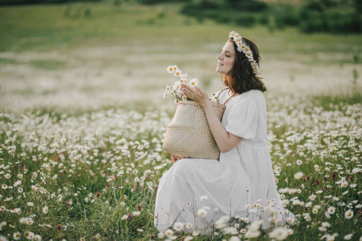 a maiden wearing white dress holding a straw basket with flowers