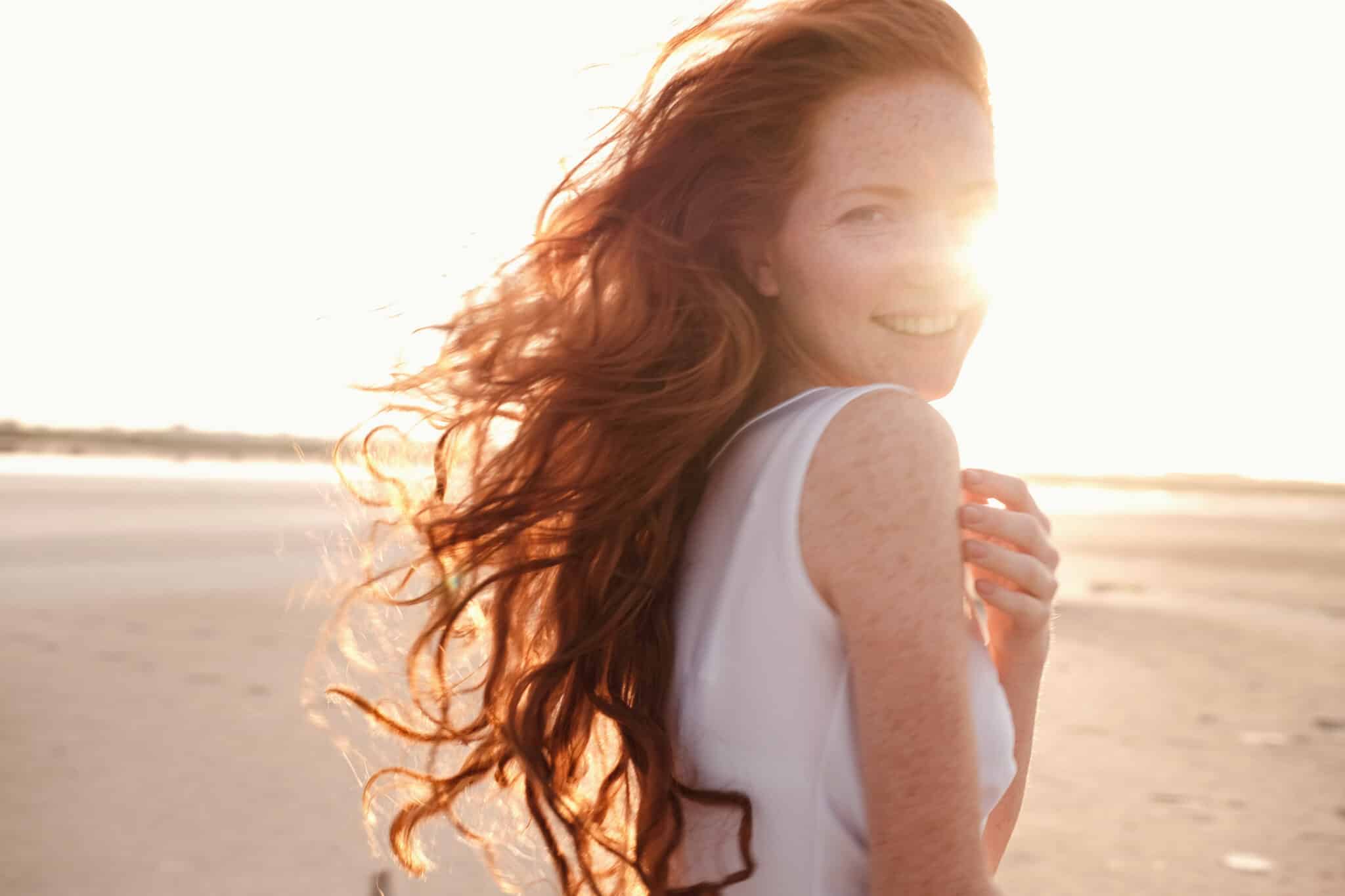 Beautiful young lady with long red hair having fun alone at sea