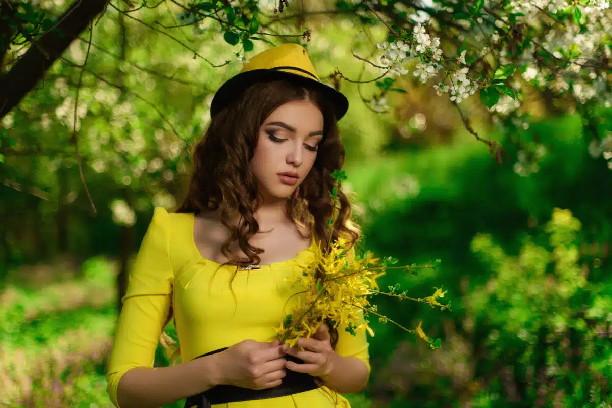 Young attractive girl in a yellow dress holding a bouquet of yellow flowers