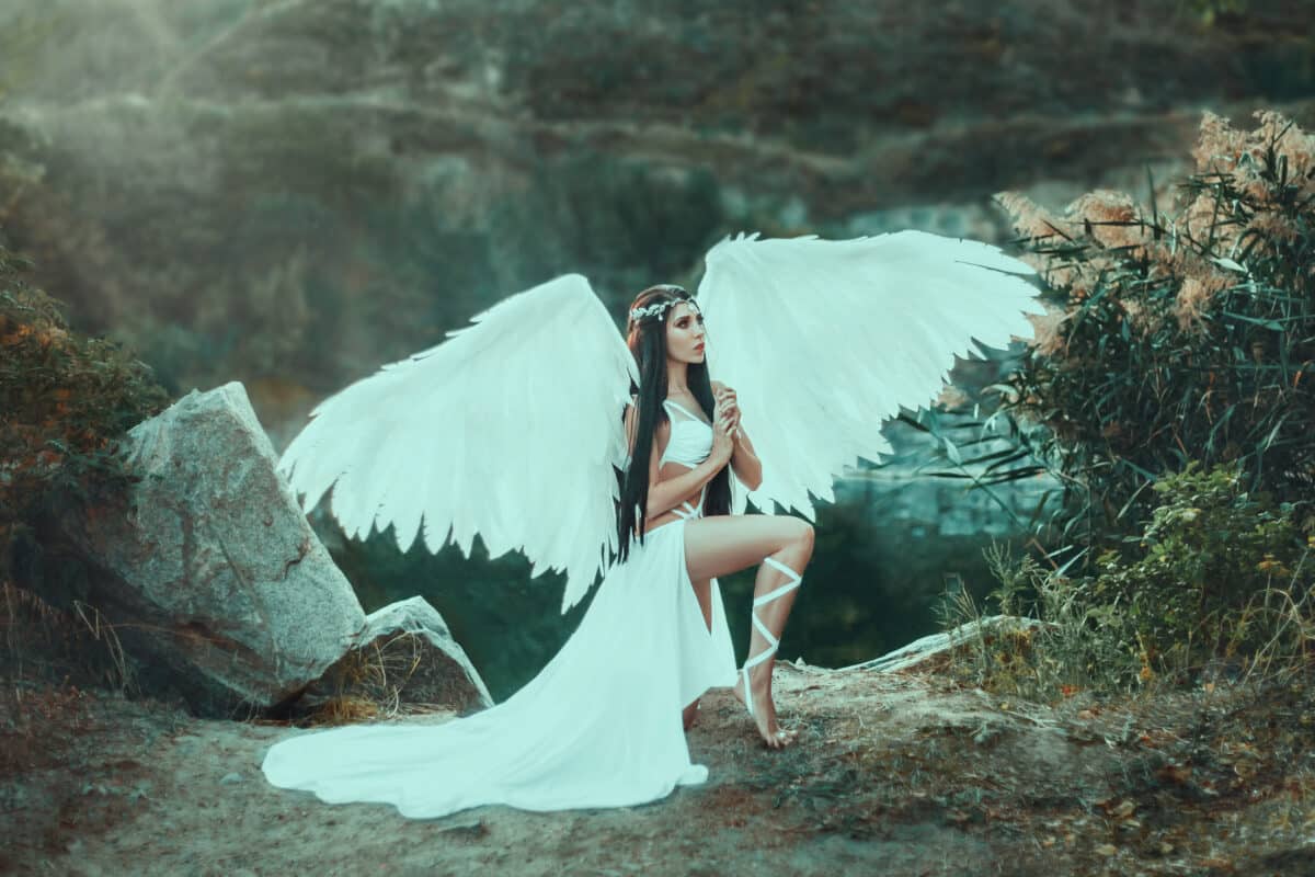 A beautiful white archangel descended from heaven. A girl in a sexy suit with huge white wings. Artistic Photography