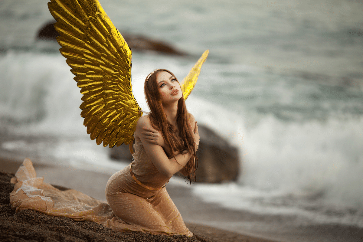 young beautiful woman fallen angel stands on sea beach enjoying nature