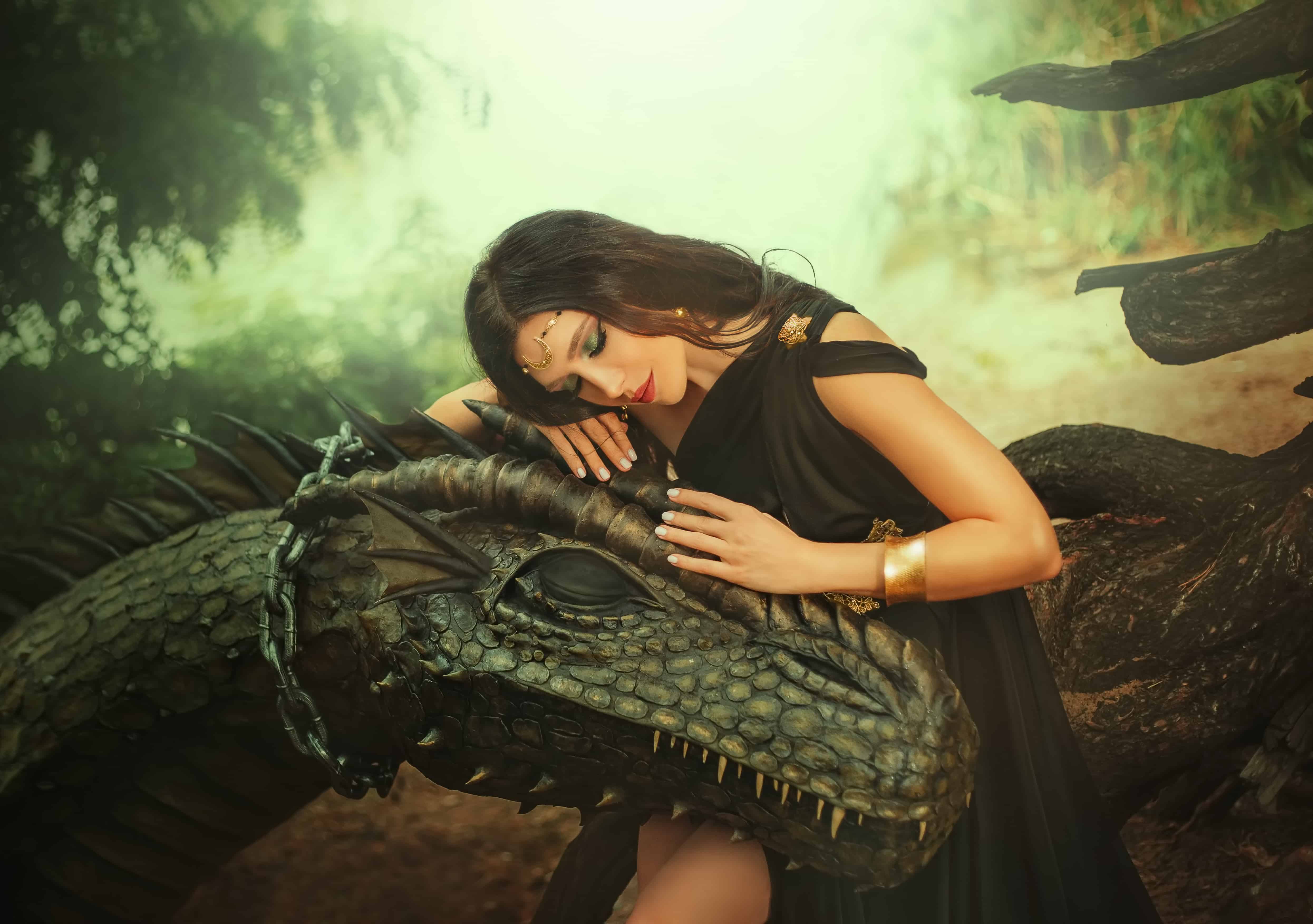 Fantasy woman evil dark queen witch hugs dragon, touching with hands head. Girl mistress tamed myth monster, concept of dominance control. black dress girl princess fashion model, golden moon diadem