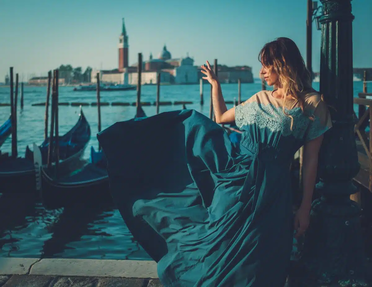 Beautiful well-dressed woman standing at a pier with gondolas