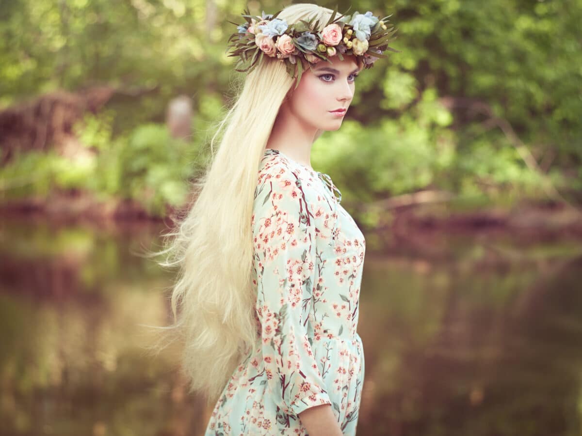 a pretty blonde woman with flower wreath on her head in the forest