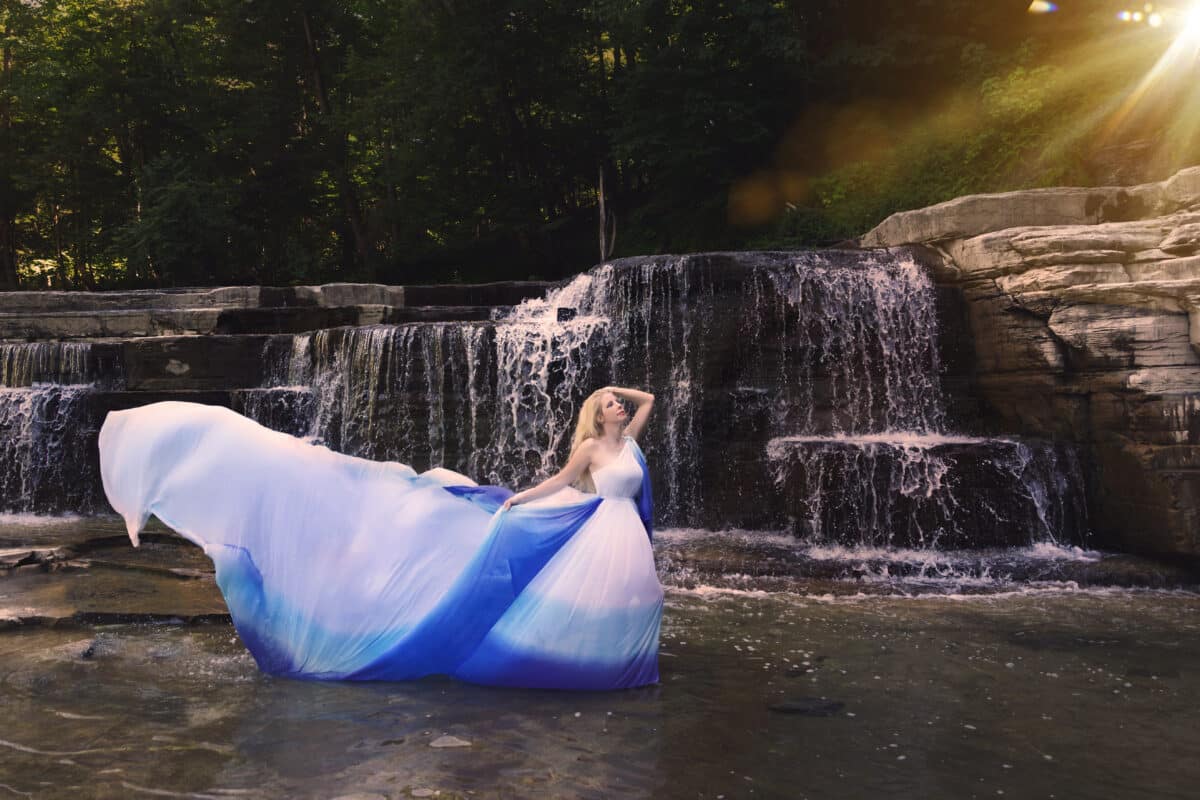 Woman in floating dress in waterfall