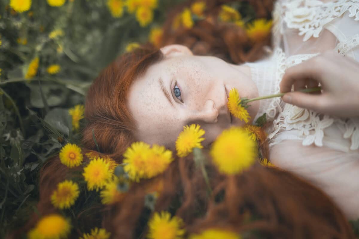 Portrait of a red-haired woman among yellow dandelions