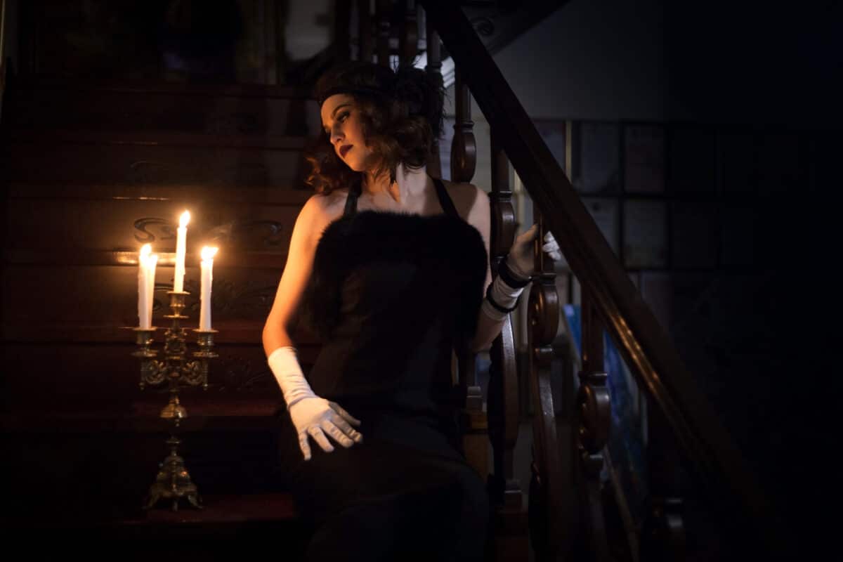 woman in a vintage black dress in the house with lit candles
