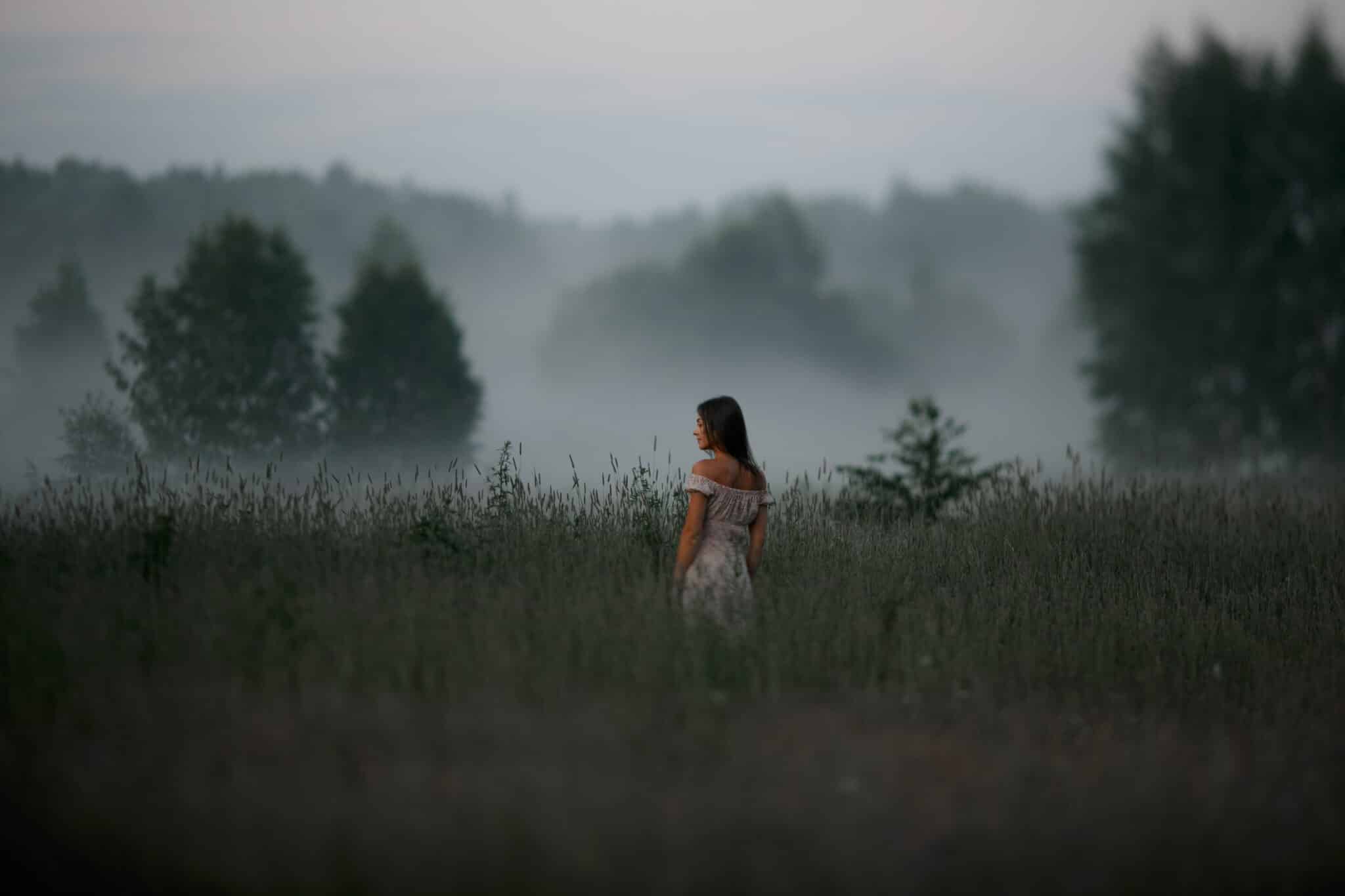 lady in a white dress standing in nature in summer fog