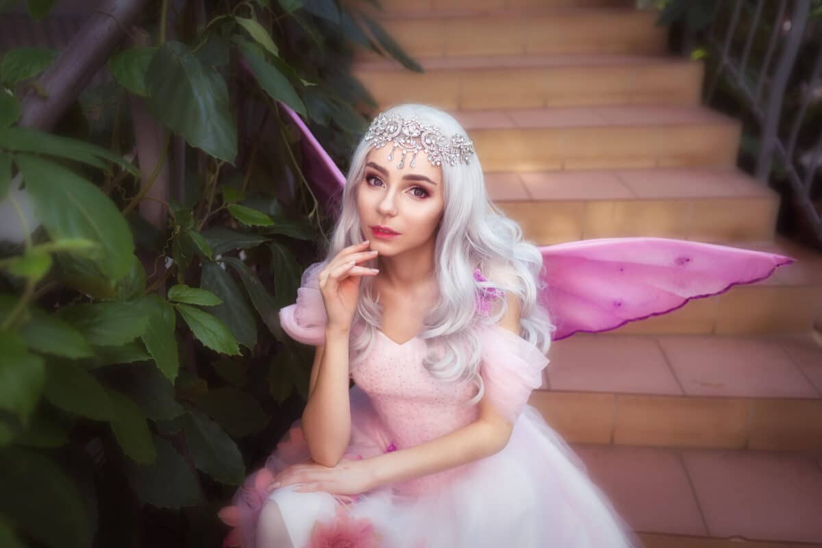 Young attractive girl dressed as fairy in green garden