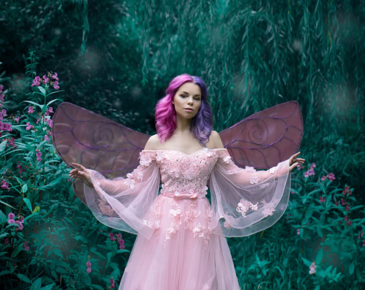 Art photo of a little forest fairy with pink hair in a fairy dress