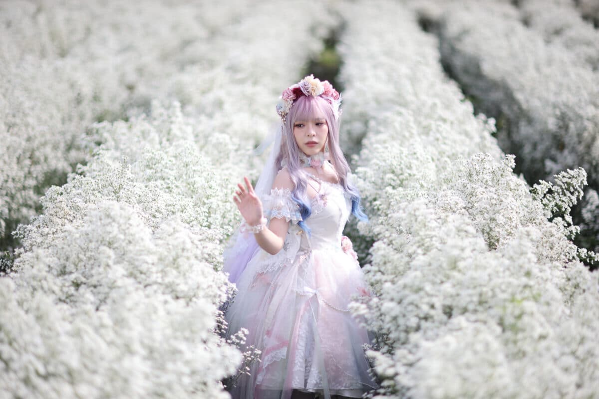Beautiful young woman with white lolita dress with flowers garden Japanese fashion