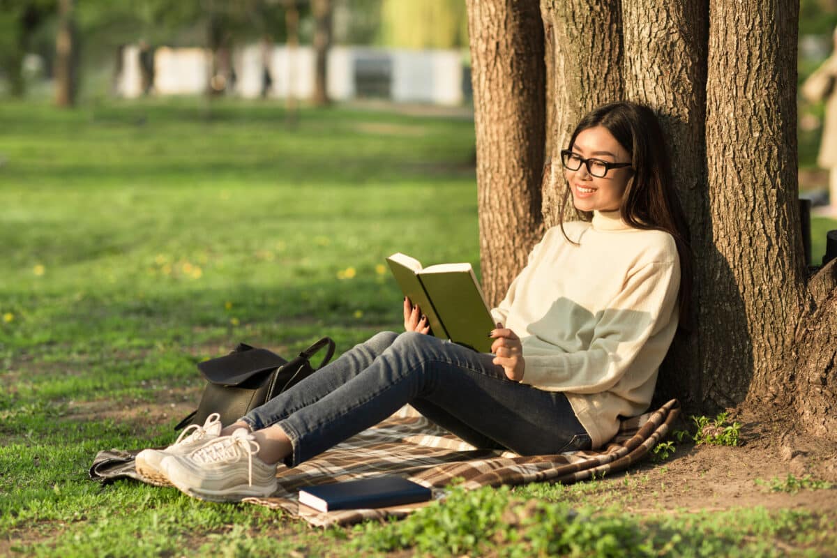 Girl reading a book sitting under the tree