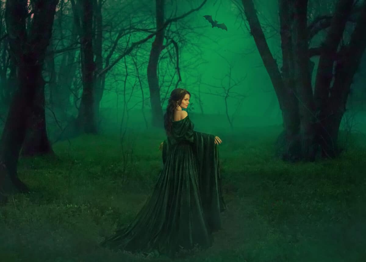 dark queen of otherworldly forces leads into realm of dead souls. bloody vampire in long velor emerald dress lures into her lair, lost pretty princess with dark hair lost her way and follows bat