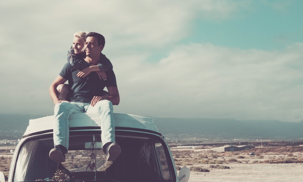 Romantic couple sitting on top of vintage car.