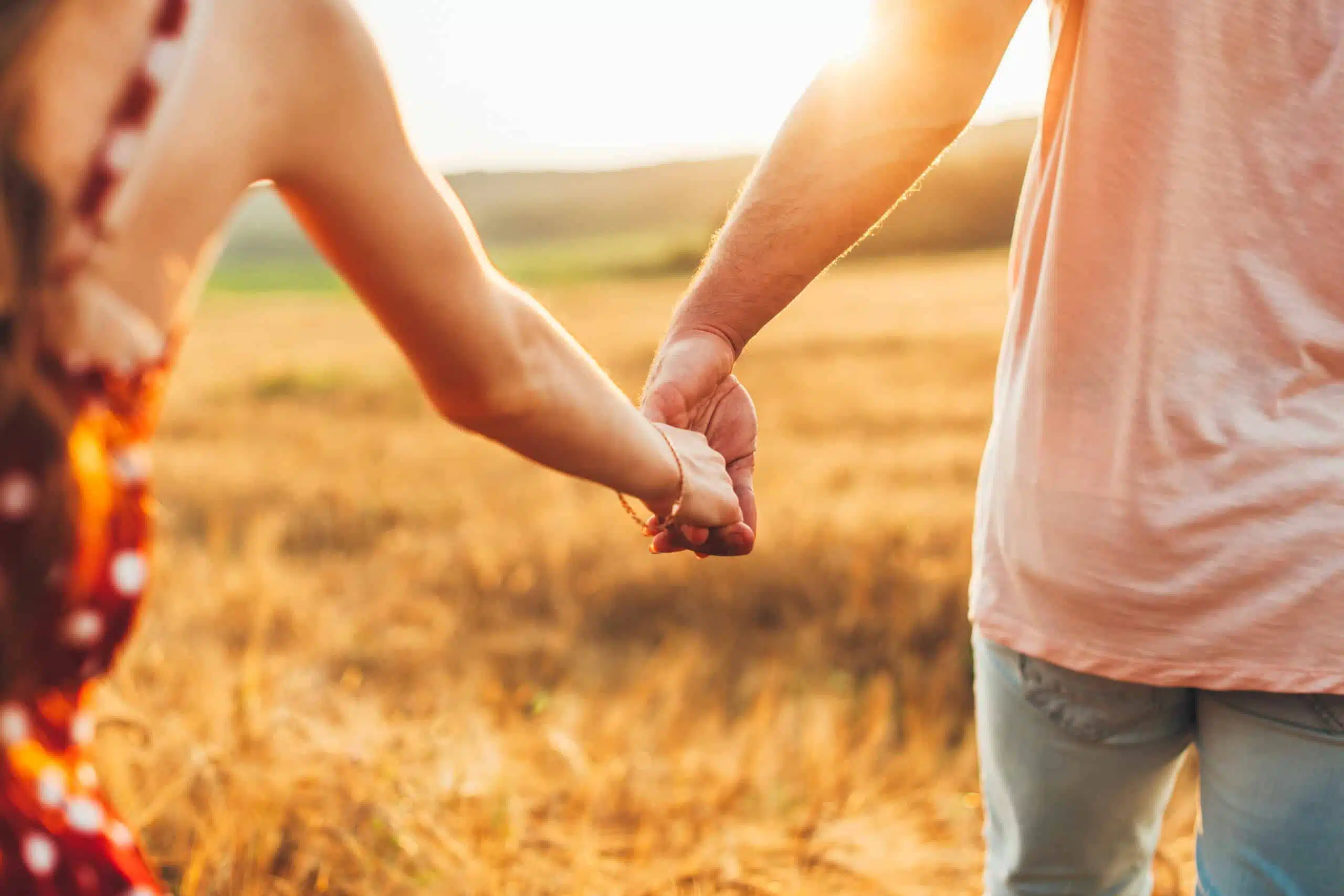 happy young couple holding hands in the wheat field