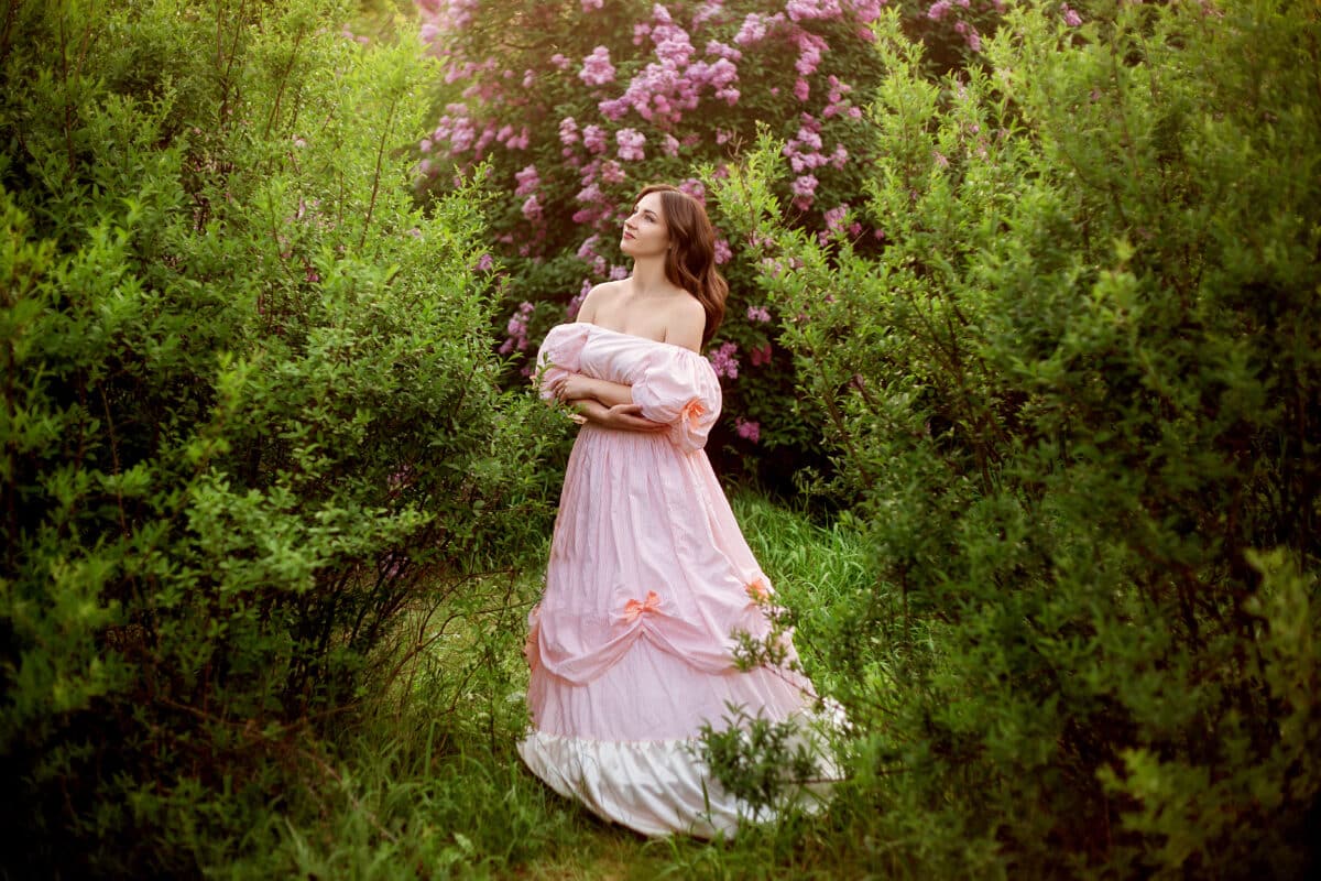 beautiful girl in a smart dress on the background of blossoming lilac and greenery