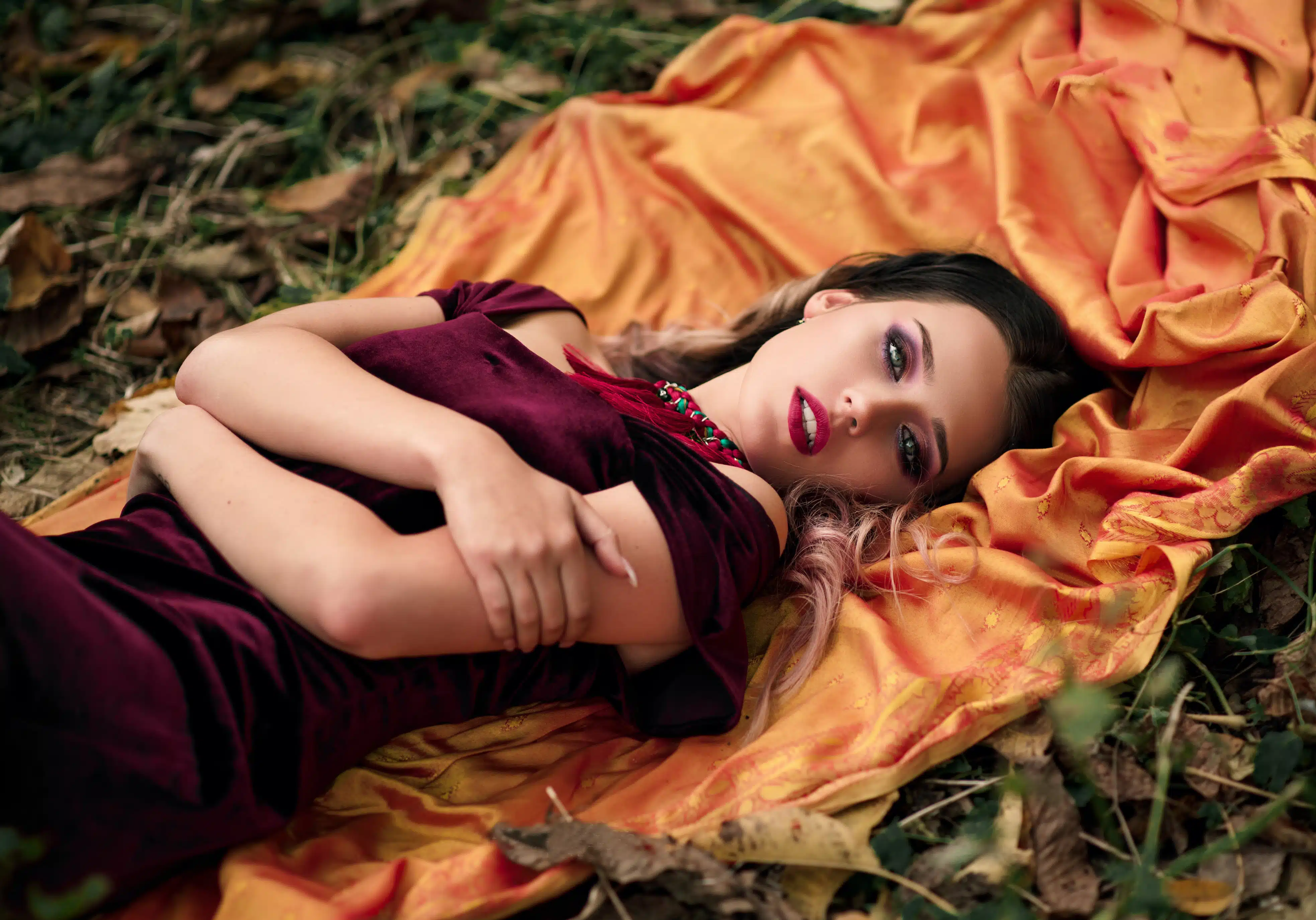 beautiful girl with green eyes and wearing velvet dress lying in the forest