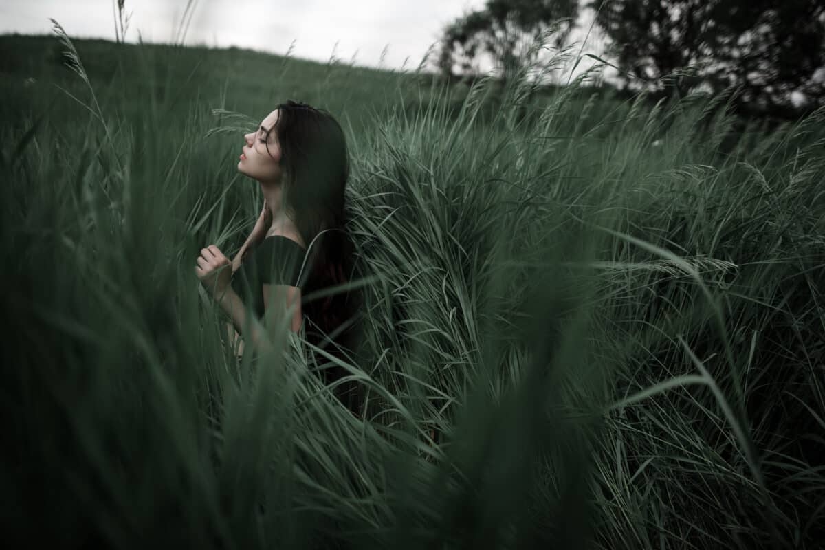 beautiful woman in black dress amidst tall grass