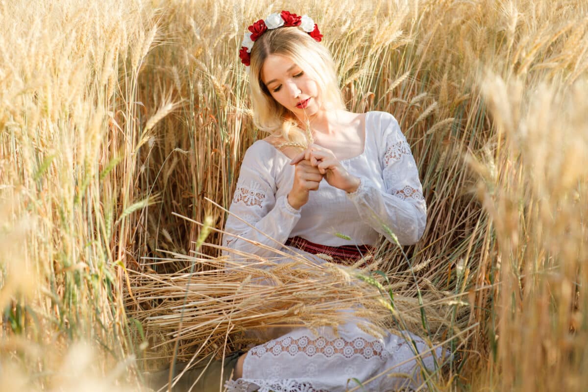 young woman with long blond hair dressed a white dress in a wheat field
