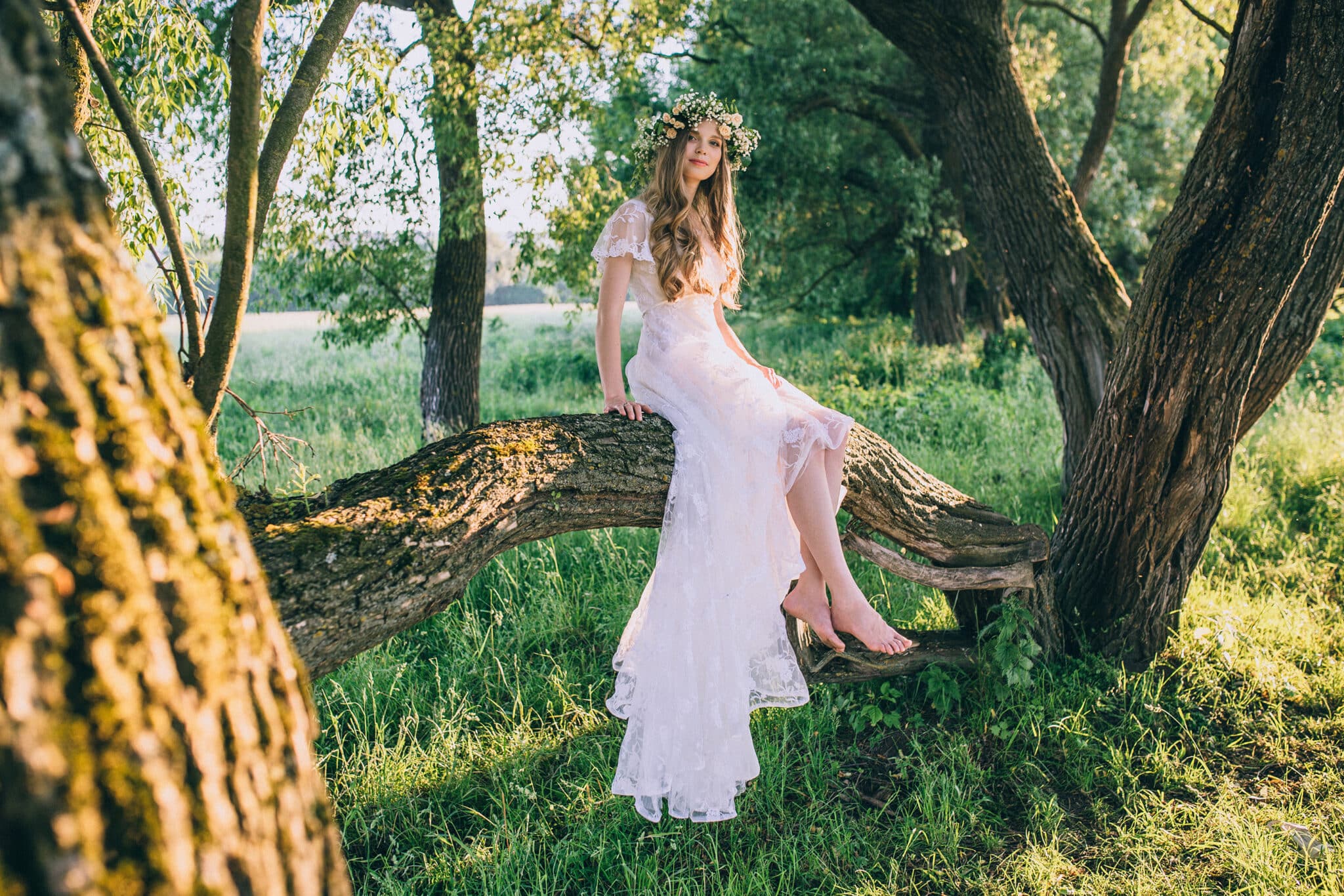 Young girl in a white dress in the meadow. Woman in a beautiful long dress posing in the garden. Stunning bride in a wedding dress