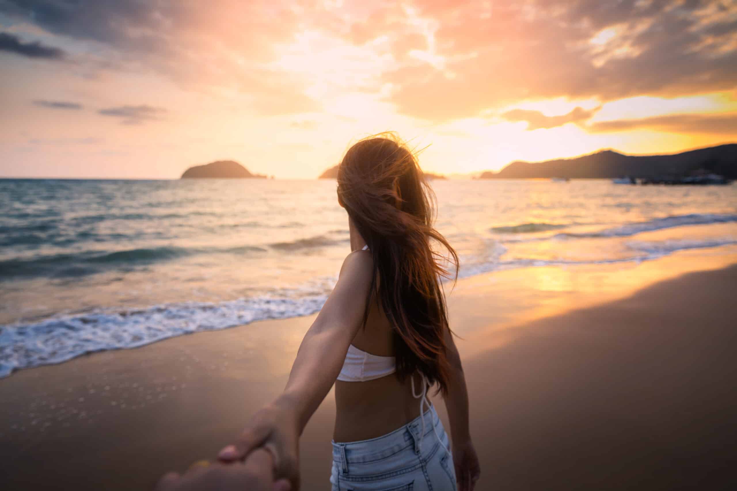Couple holding hands on beach in sunset
