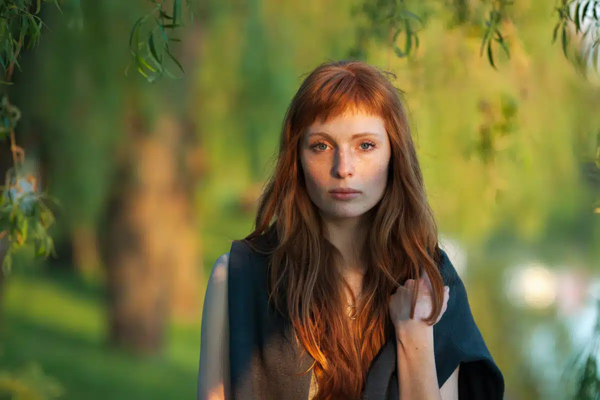 melancholic young redhead lady standing in nature