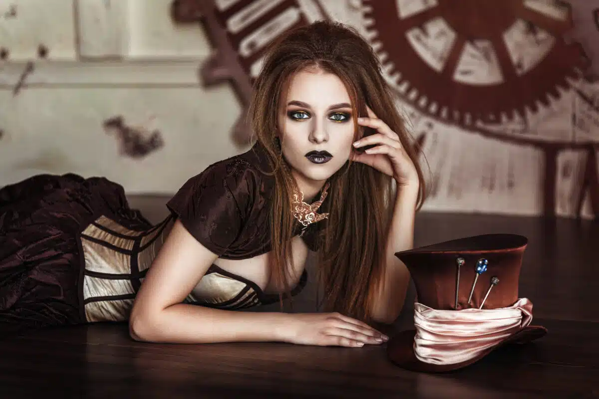 a beautiful steampunk woman sitting at a desk with a wheel behind her