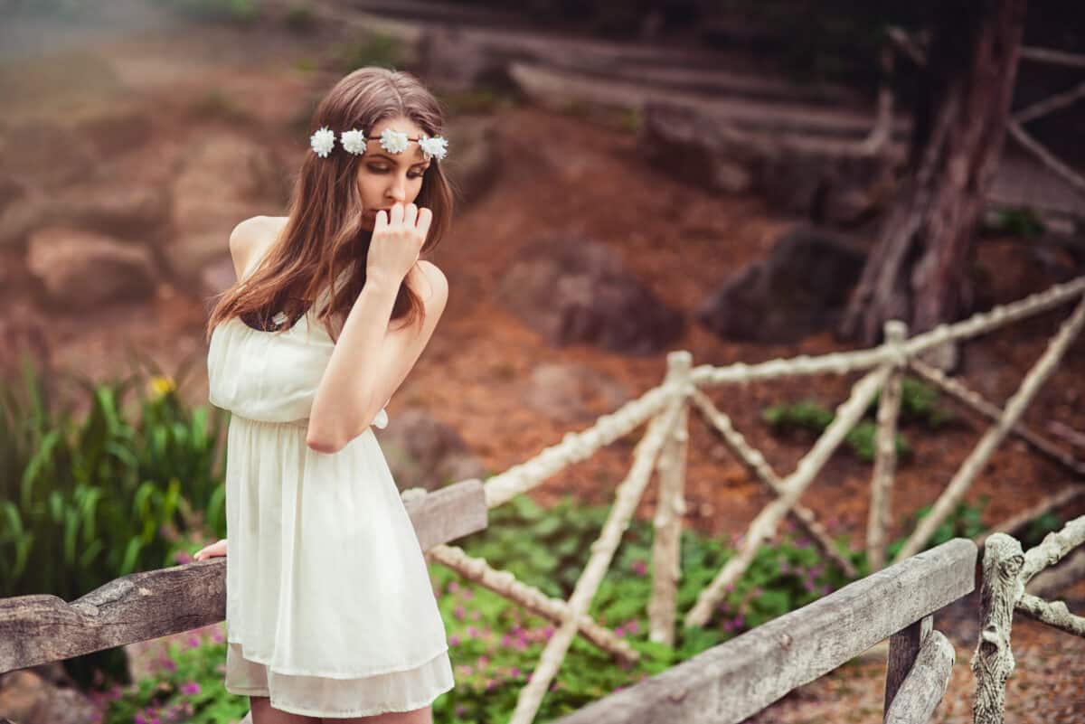 Beautiful sad woman with flower head wreath in nature