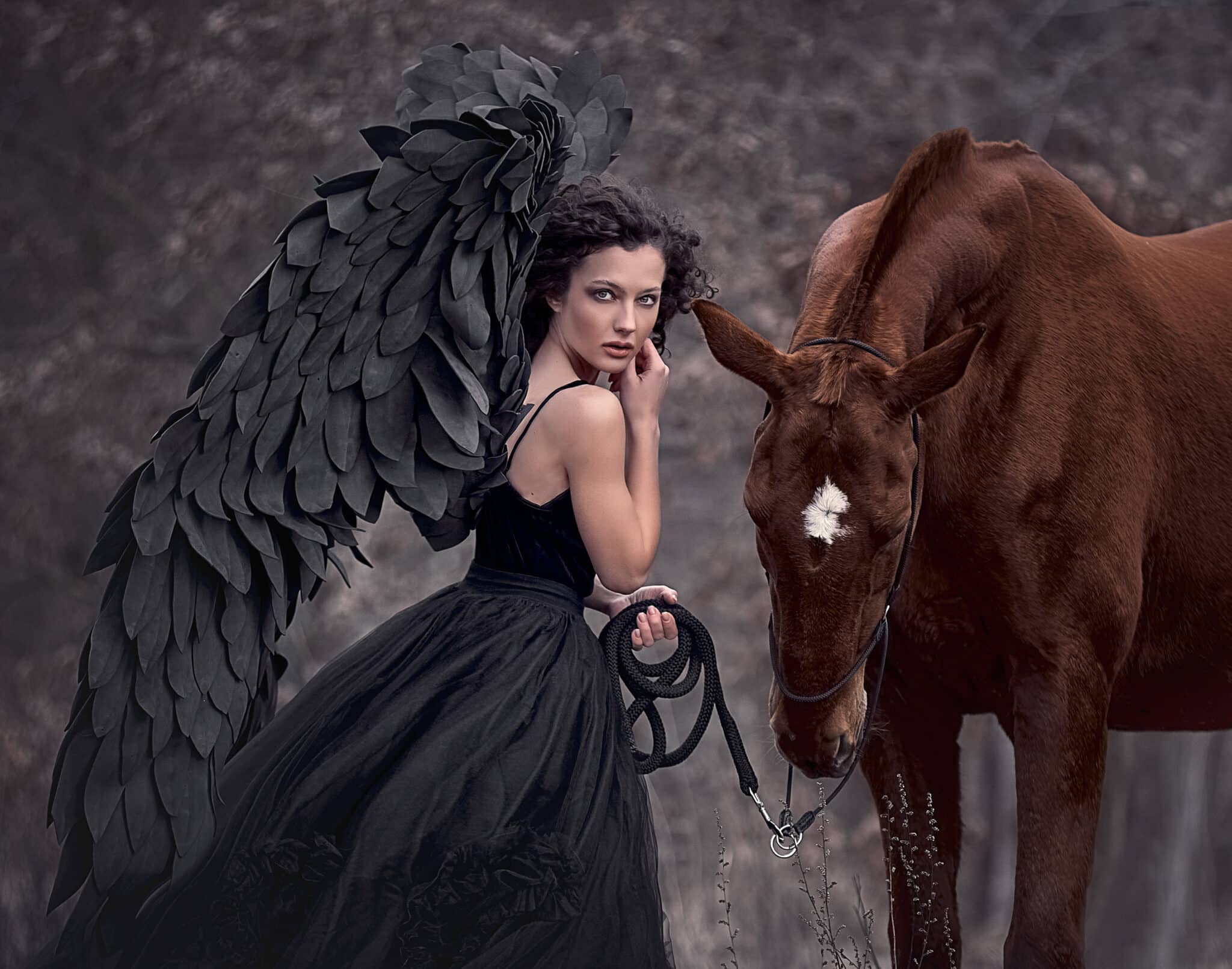 Beautiful black angel next to a brown horse