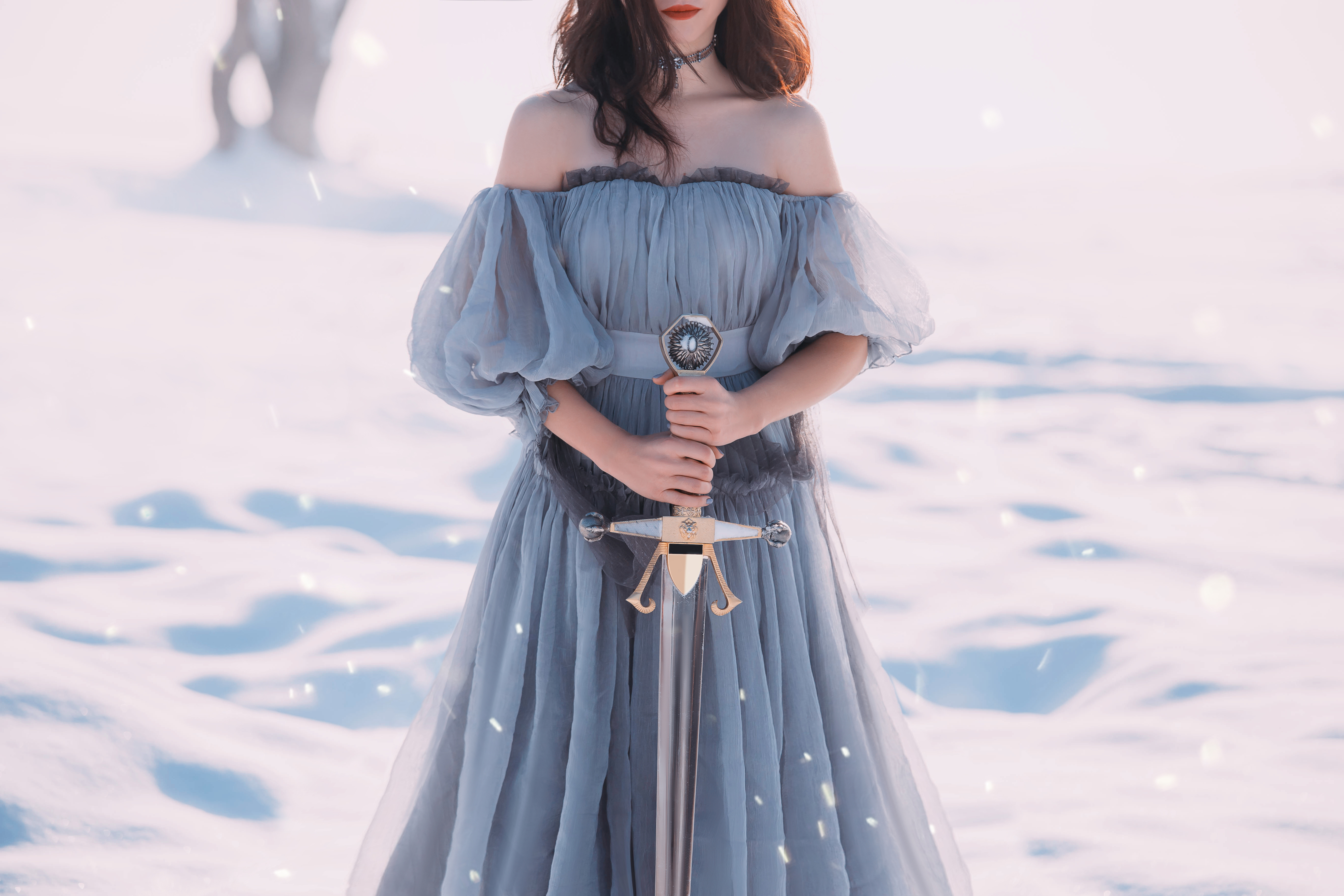 lady holding a sharp silver sword in hands standing in the snow