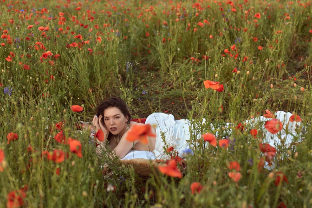A young girl relaxing in a flowering poppy field