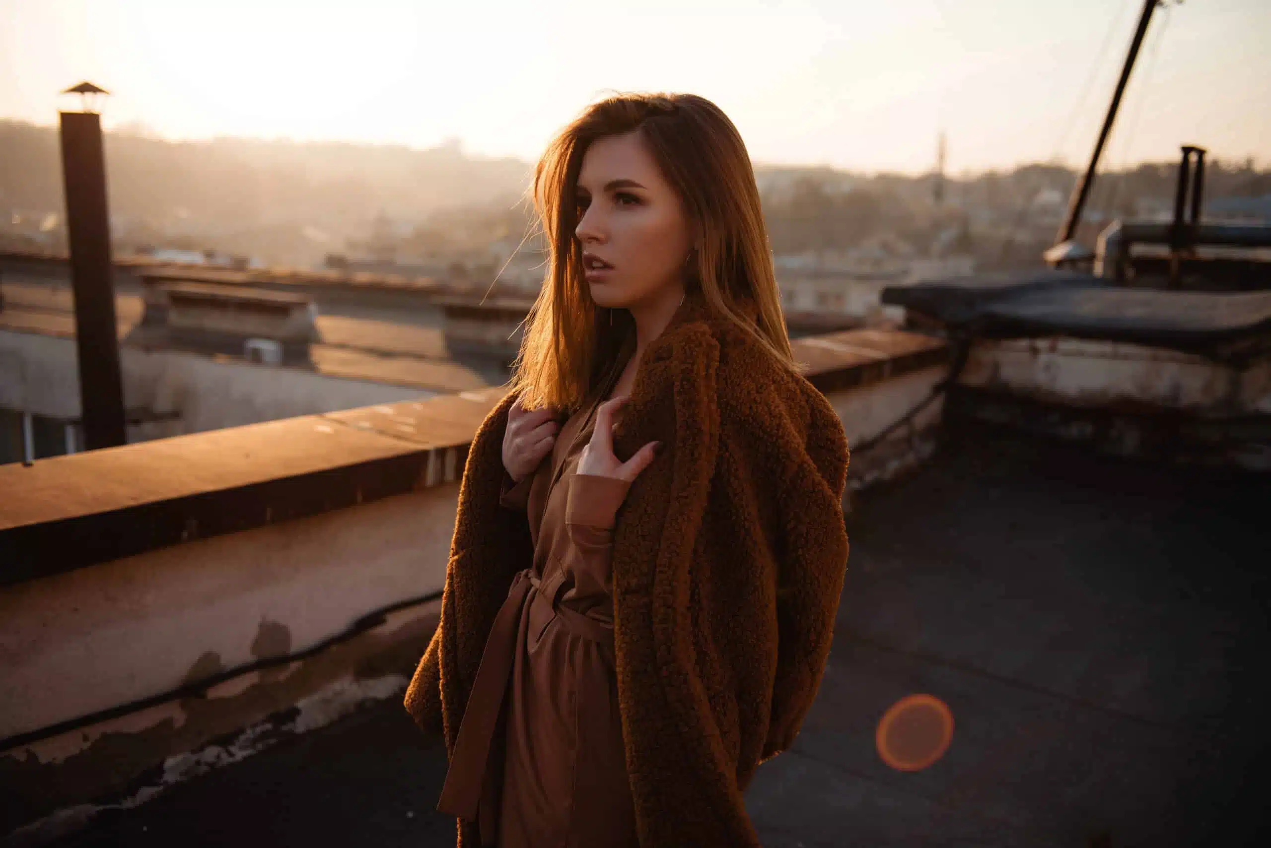 melancholic young woman in dress on rooftop at sunset